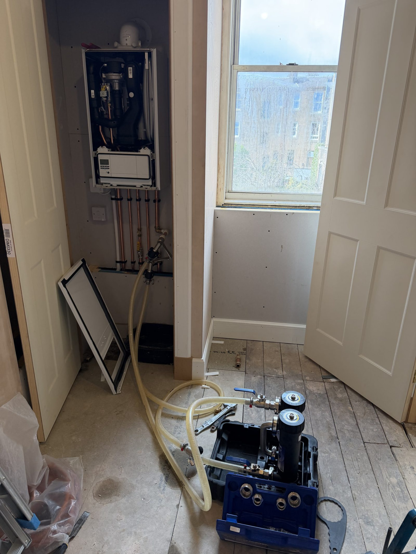 Power flushing pump and magnetic filter connected by hoses to a boiler during a central heating power flush in Edinburgh
